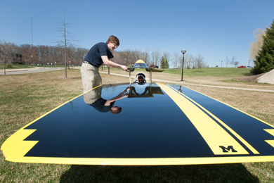 University of Michigan solar car team interim operations director Aaron Frantz, a sophomore mechanical engineering student, helps load driver Santosh Kumar into the 2011 solar car Quantum. Kumar, a master's student in aerospace engineering, is the team's engineering director. (Photo: Scott Soderberg, U-M Photo Services.)