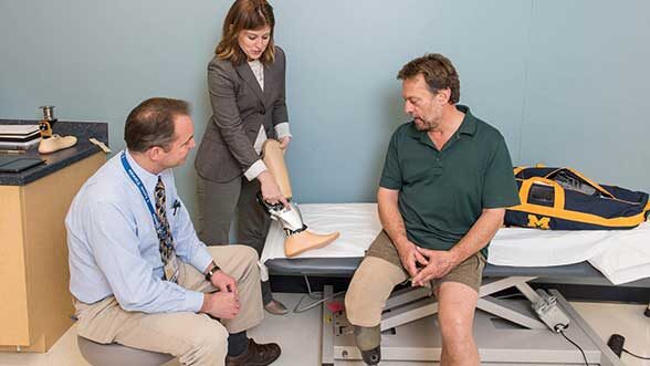 Jeffrey Wensman and Deanna Gates, assistant professor, Director of the Rehabilitation Biomechanics Laboratory at the University of Michigan help fit Roger Schulte (right) with a prosthesis. (Image: Scott C. Soderberg, Michigan Photography.)