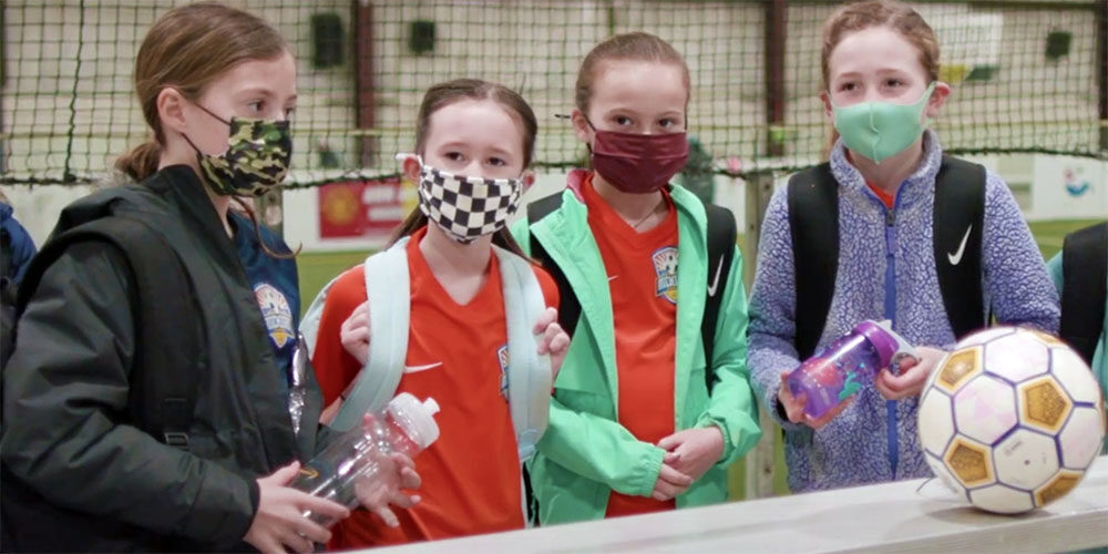 Girls in masks prepare to play soccer