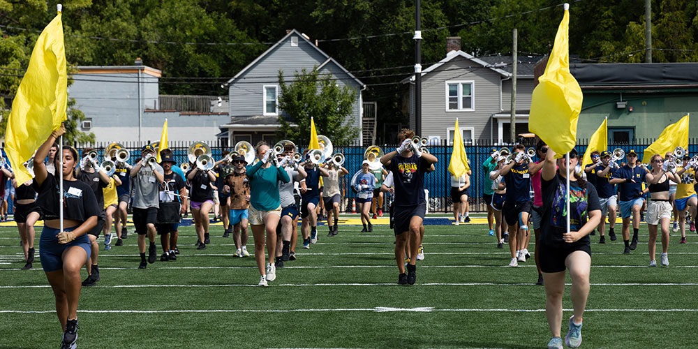 Michigan Marching band practices at Elbel with yellow flags.