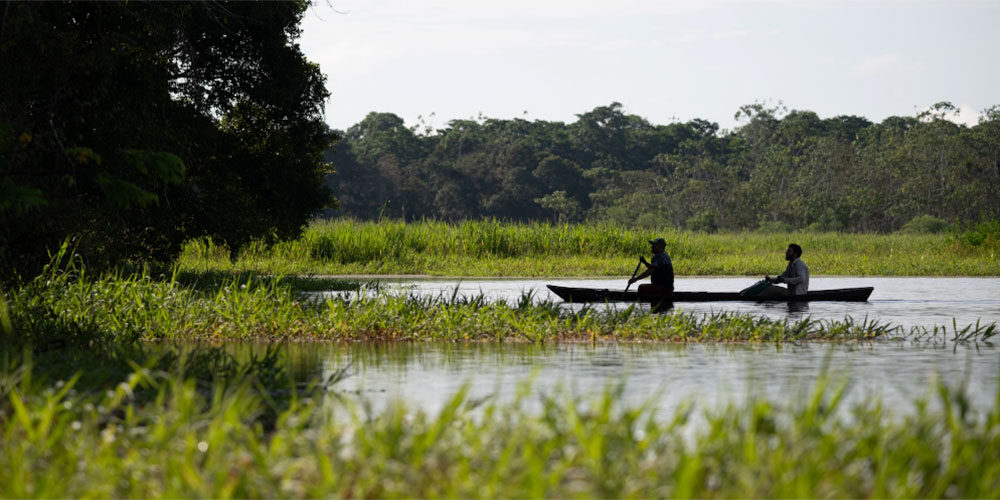 Two people row a canoe-like boat in the Amazon in Brazil.