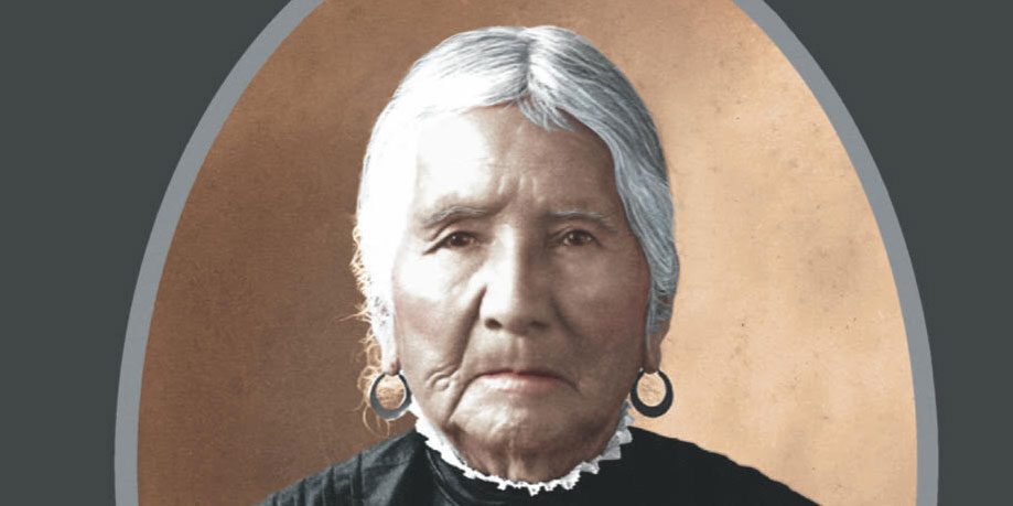 Portrait of Native American woman with white hair, hoop earrings, high collar.