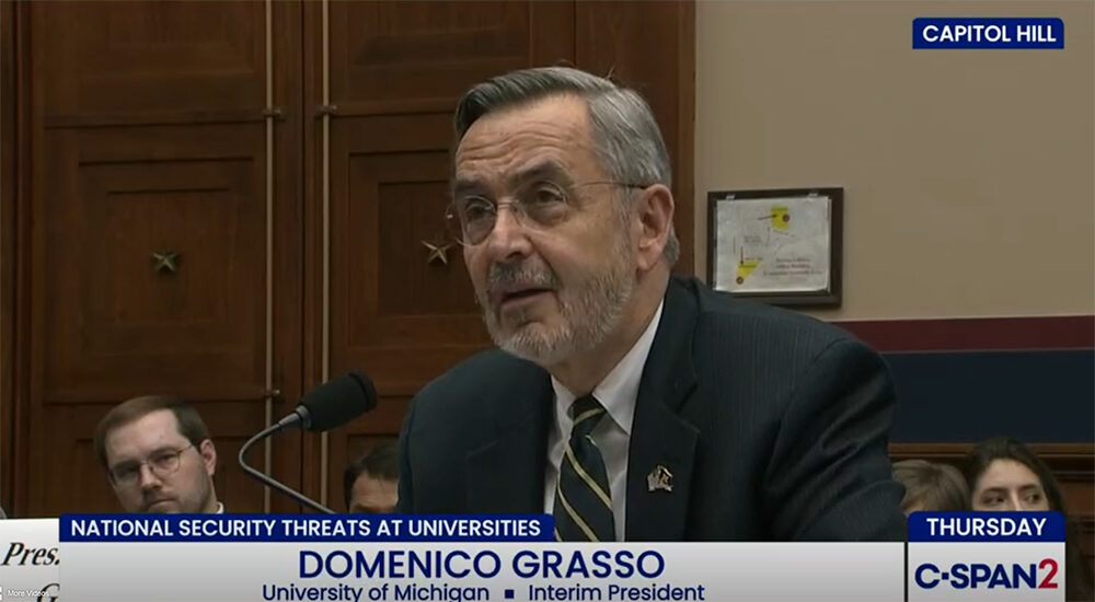 University of Michigan President Domenico Grasso testifies before Congress in March 2026. He is a silver-haired man wearing glasses, seated before a microphone, wearing a striped tie and dark suit.
