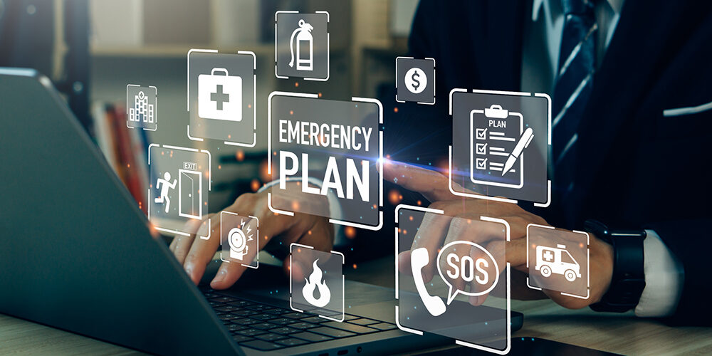 Stock photo shows hands on a keyboard surrounded by symbols regarding emergencies, SOS, plans, etc.